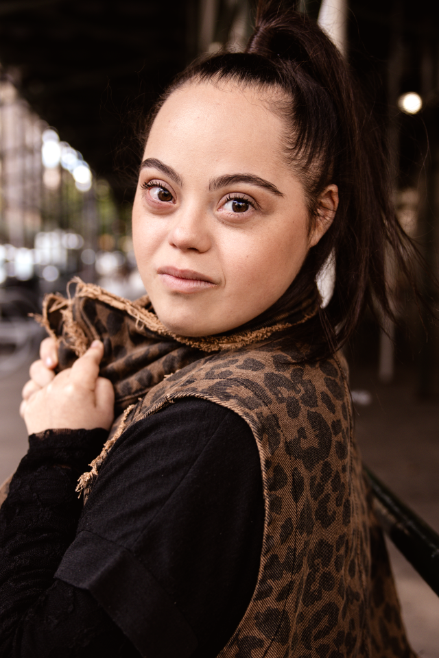 Madison wearing a leopard print vest and holding a scarf outdoors