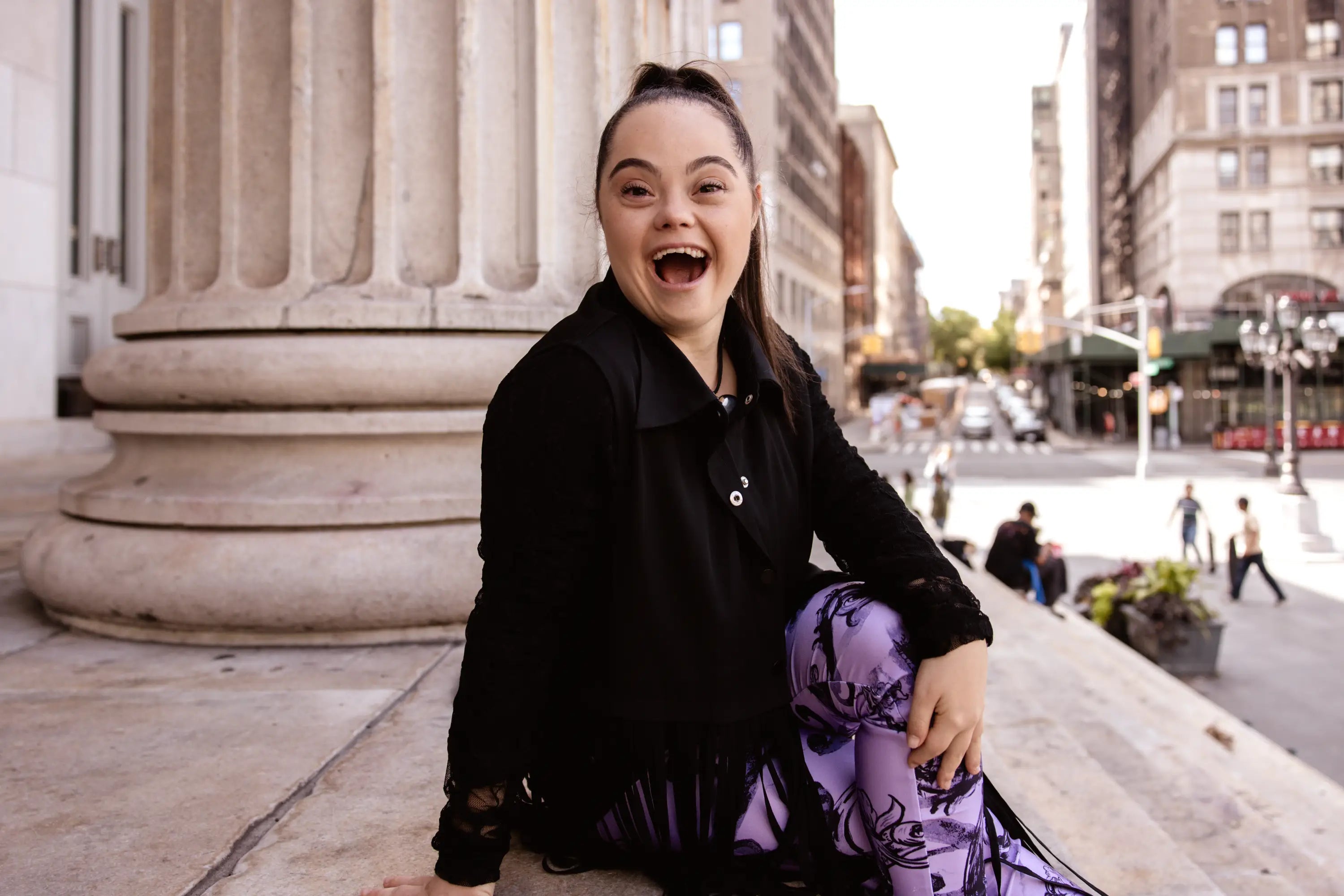 Madison sitting on a city street with classical architecture in the background
